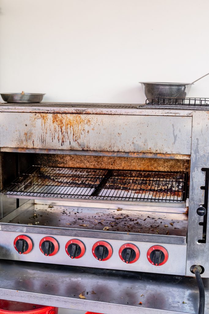 A stainless steel oven with accumulated grime deposits